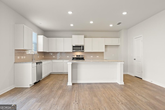 kitchen featuring a sink, stainless steel appliances, baseboards, white cabinetry, and backsplash