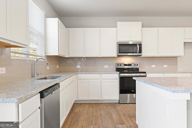 kitchen with stainless steel appliances, white cabinetry, and a sink
