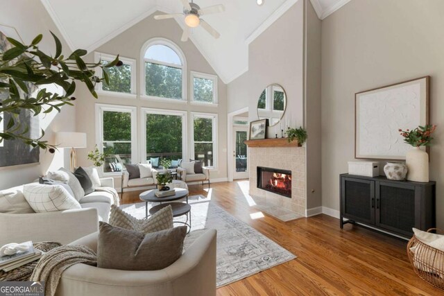 12892 Waterside Dr, Milton, GA 30004 - living area featuring ornamental molding, wood finished floors, high vaulted ceiling, a tile fireplace, and a ceiling fan