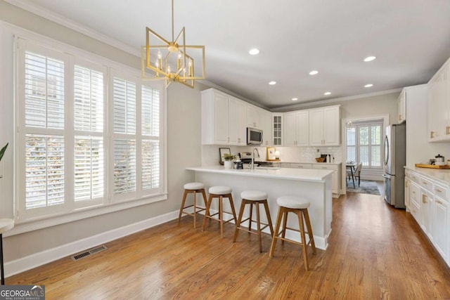 12892 Waterside Dr, Milton, GA 30004 - kitchen with visible vents, a peninsula, ornamental molding, stainless steel appliances, and recessed lighting