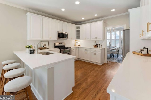 12892 Waterside Dr, Milton, GA 30004 - kitchen with a peninsula, glass insert cabinets, a kitchen bar, a sink, and appliances with stainless steel finishes