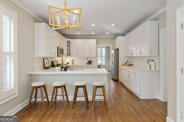 12892 Waterside Dr, Milton, GA 30004 - kitchen with stainless steel appliances, a peninsula, tasteful backsplash, a breakfast bar, and glass insert cabinets