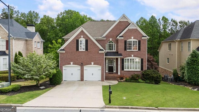 12892 Waterside Dr, Milton, GA 30004 - traditional home featuring a front lawn, cooling unit, brick siding, an attached garage, and driveway