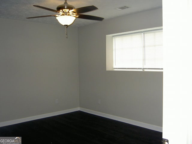214 Oak Cir, Stockbridge, GA 30281 - spare room featuring baseboards, a ceiling fan, dark wood-style flooring, and visible vents