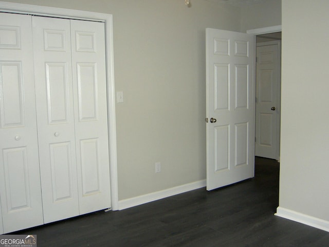 214 Oak Cir, Stockbridge, GA 30281 - unfurnished bedroom with baseboards, a closet, and dark wood-style flooring
