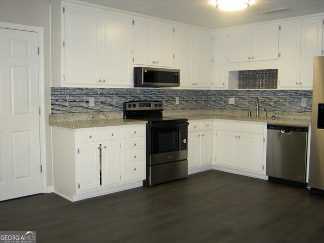 214 Oak Cir, Stockbridge, GA 30281 - kitchen with appliances with stainless steel finishes, white cabinets, backsplash, and dark wood finished floors