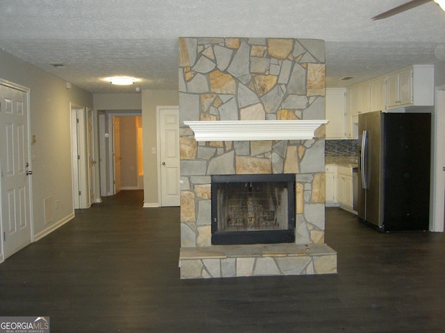 214 Oak Cir, Stockbridge, GA 30281 - unfurnished living room with ceiling fan, a fireplace, a textured ceiling, baseboards, and dark wood-style floors