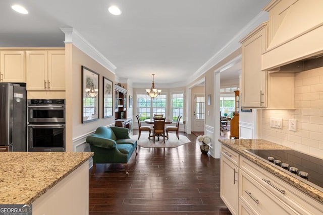 kitchen featuring stainless steel appliances, a notable chandelier, ornamental molding, and cream cabinetry