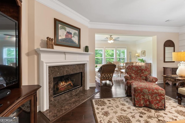 living room featuring crown molding, a premium fireplace, ceiling fan, and hardwood / wood-style flooring