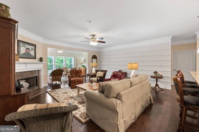 living area with ornamental molding, ceiling fan, dark wood-type flooring, recessed lighting, and a premium fireplace