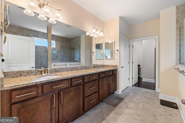 bathroom featuring double vanity, tiled shower, a sink, and visible vents