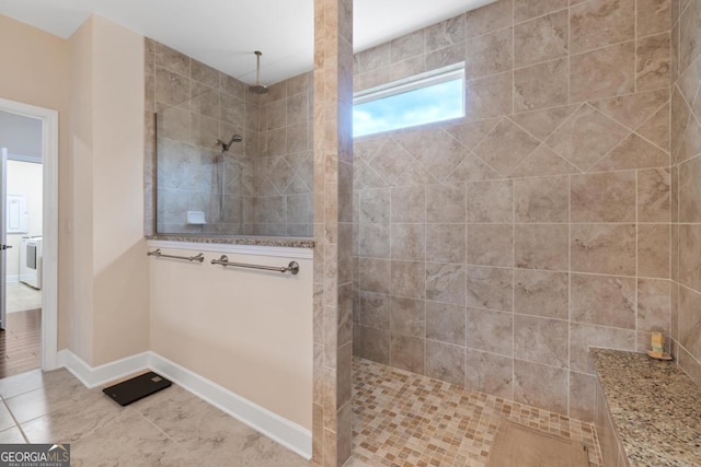 bathroom with baseboards, washer / dryer, walk in shower, and tile patterned floors