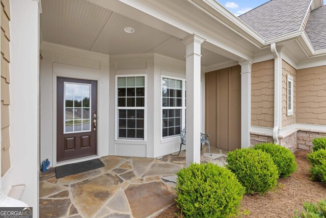 property entrance featuring a shingled roof and a porch