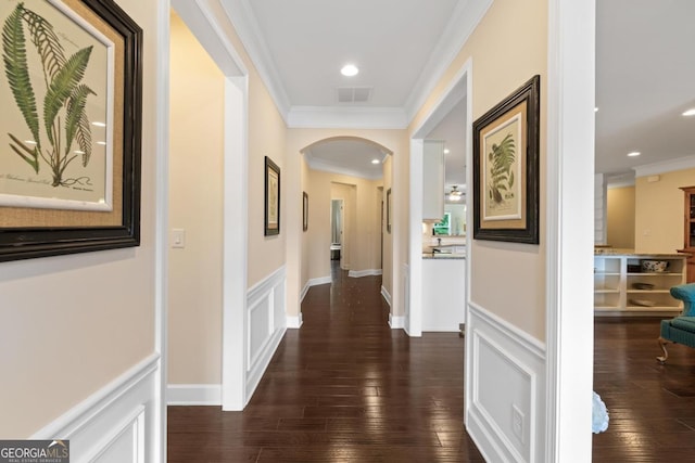 hall featuring arched walkways, visible vents, ornamental molding, and a wainscoted wall