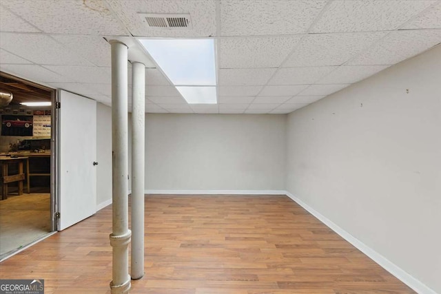 finished basement with wood finished floors, baseboards, and a drop ceiling