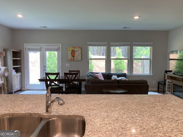 kitchen featuring baseboards, open floor plan, plenty of natural light, and a sink
