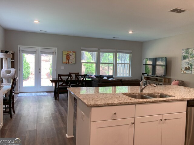 kitchen featuring light stone counters, a sink, french doors, open floor plan, and visible vents