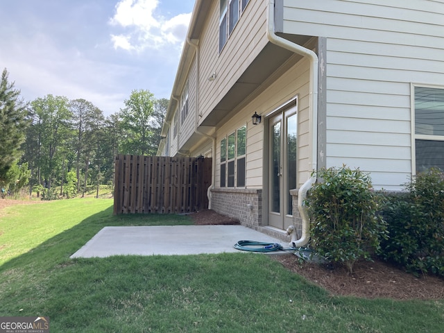 view of property exterior featuring a lawn, a patio area, fence, and french doors