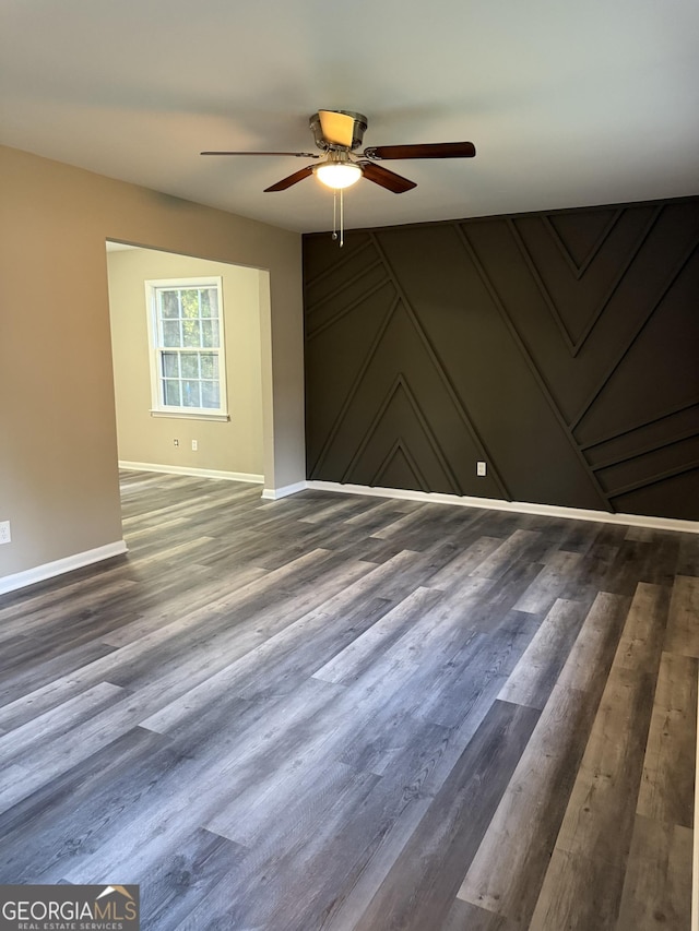 empty room featuring baseboards, a ceiling fan, and wood finished floors