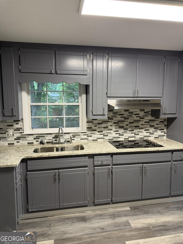 kitchen with a sink, gray cabinets, tasteful backsplash, and black electric cooktop