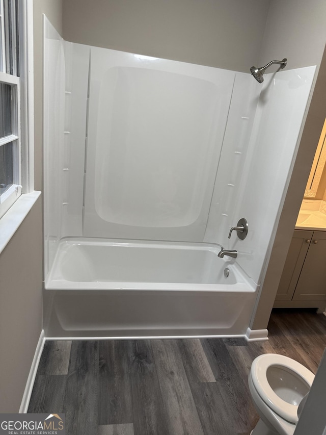 full bath featuring vanity, bathtub / shower combination, toilet, baseboards, and wood finished floors