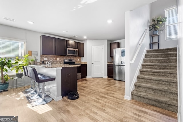 400 Toronto Cir, Hampton, GA 30228 - kitchen with dark brown cabinets, appliances with stainless steel finishes, a kitchen breakfast bar, a peninsula, and tasteful backsplash