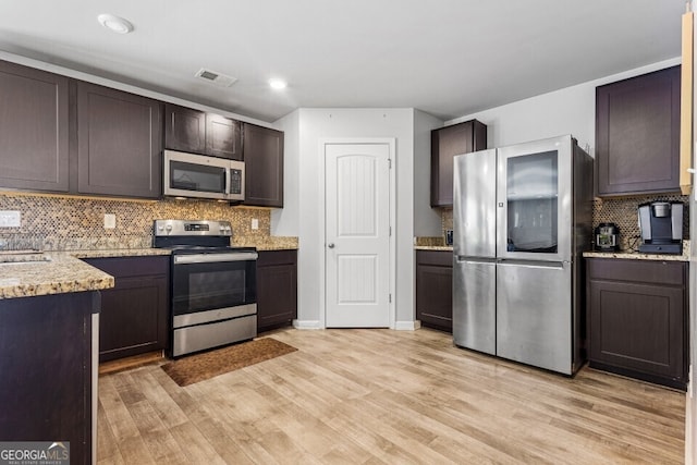 400 Toronto Cir, Hampton, GA 30228 - kitchen with visible vents, tasteful backsplash, light stone counters, light wood-style flooring, and stainless steel appliances