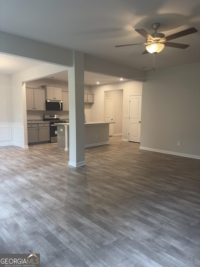 1155 Park Center Cir NW, Austell, GA 30168 - unfurnished living room with a wainscoted wall, ceiling fan, baseboards, and dark wood finished floors