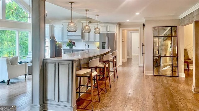 kitchen featuring plenty of natural light, light countertops, a breakfast bar, and stainless steel fridge with ice dispenser