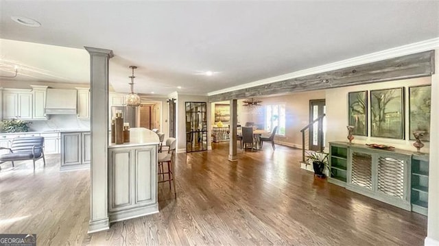living area with crown molding, decorative columns, wood finished floors, baseboards, and recessed lighting