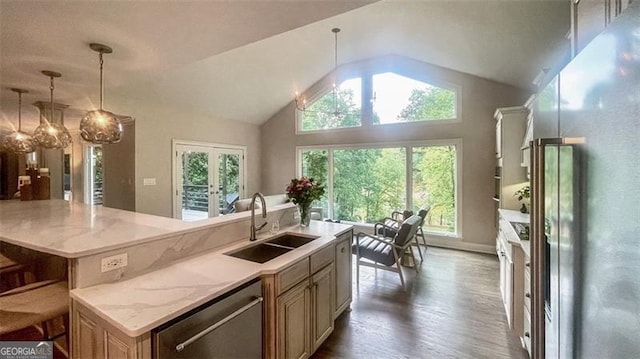 kitchen featuring appliances with stainless steel finishes, vaulted ceiling, a center island with sink, wood finished floors, and a sink