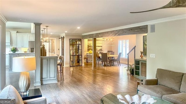living room featuring baseboards, a chandelier, ornamental molding, and wood finished floors