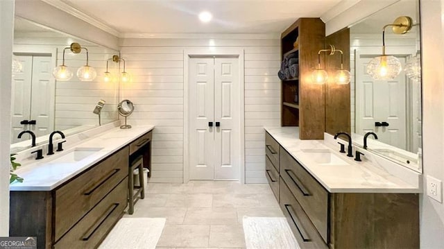 full bath with a sink, crown molding, and two vanities