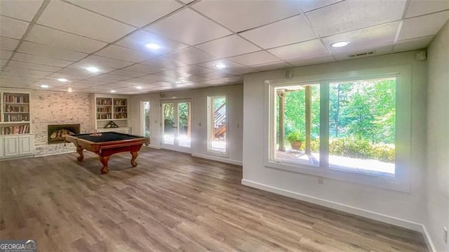 playroom with built in features, a stone fireplace, baseboards, a drop ceiling, and billiards