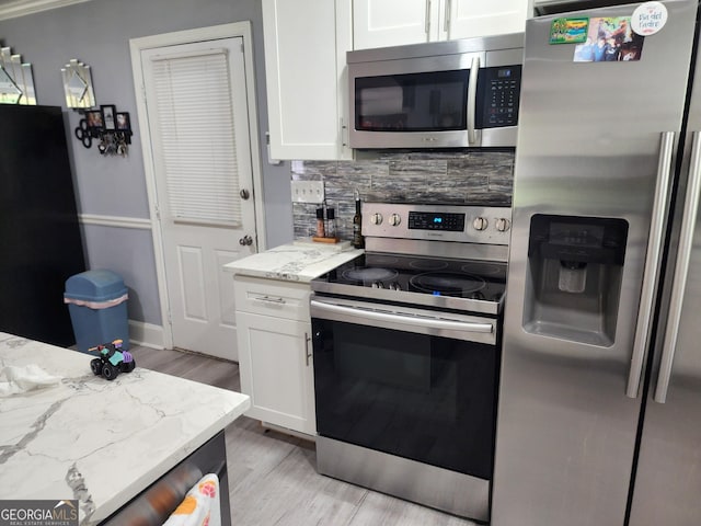 kitchen featuring light stone countertops, white cabinets, light wood finished floors, backsplash, and stainless steel appliances