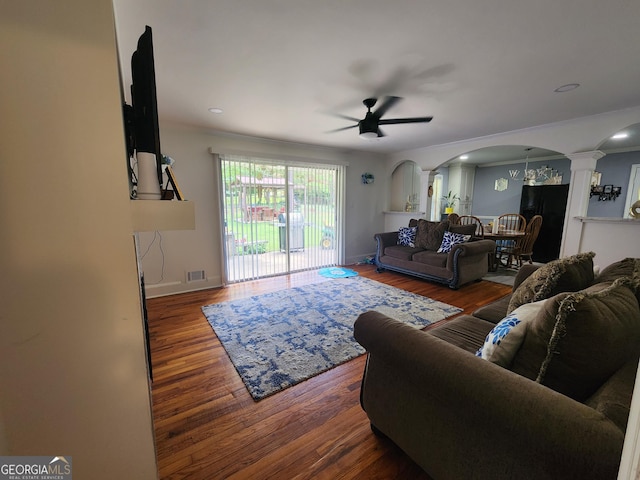 living area featuring arched walkways, a ceiling fan, wood finished floors, ornate columns, and visible vents