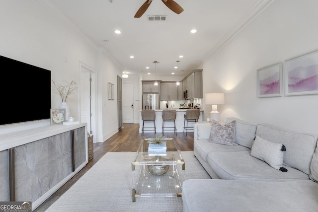 living area featuring ornamental molding, ceiling fan, dark wood-type flooring, recessed lighting, and baseboards