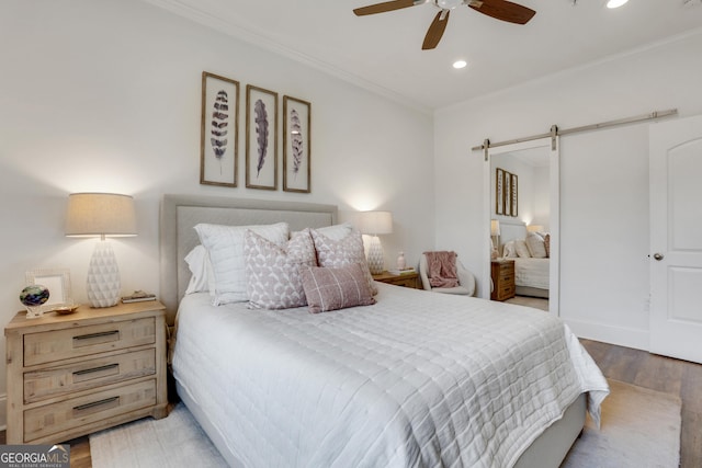 bedroom featuring wood finished floors, recessed lighting, ornamental molding, a barn door, and a ceiling fan
