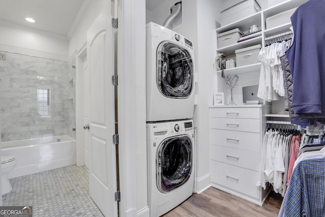 laundry room featuring estacked washer and dryer, wood finished floors, and recessed lighting
