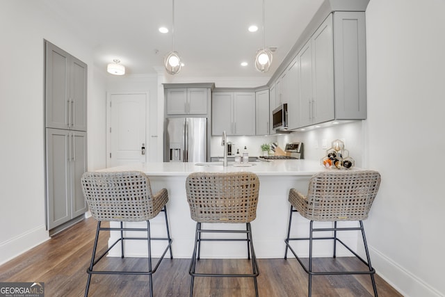 kitchen featuring stainless steel appliances, gray cabinetry, a sink, a peninsula, and light countertops