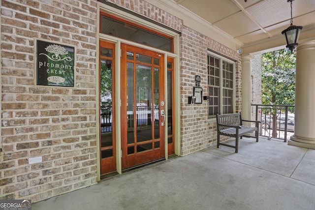 entrance to property with a porch and brick siding