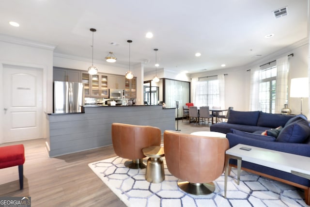 living room featuring ornamental molding, light wood-style flooring, and recessed lighting