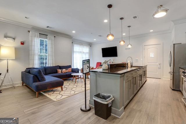 kitchen with gray cabinetry, open floor plan, a sink, ornamental molding, and freestanding refrigerator