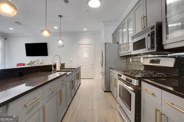 kitchen featuring stainless steel appliances, gray cabinets, a sink, ornamental molding, and decorative backsplash
