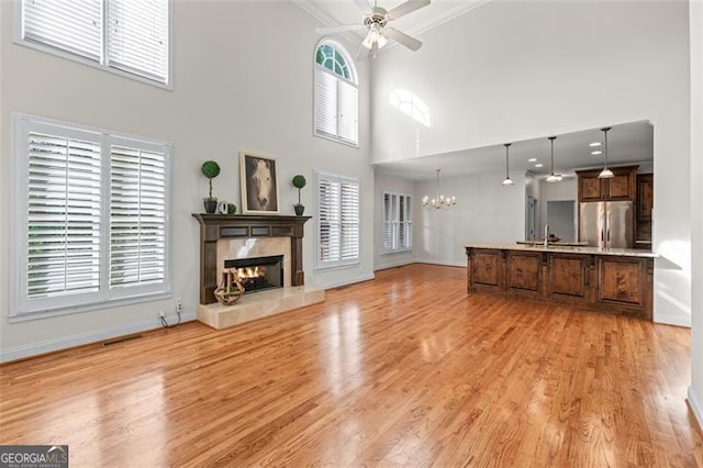4876 Sara Creek Way, Sugar Hill, GA 30518 - unfurnished living room with a tiled fireplace, baseboards, ceiling fan with notable chandelier, and a healthy amount of sunlight