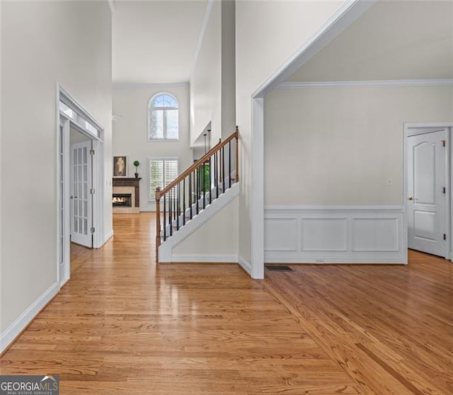 4876 Sara Creek Way, Sugar Hill, GA 30518 - foyer featuring crown molding, light wood finished floors, stairs, and a warm lit fireplace