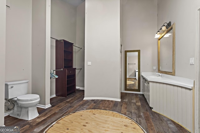 bathroom with vanity, baseboards, wood finished floors, and toilet