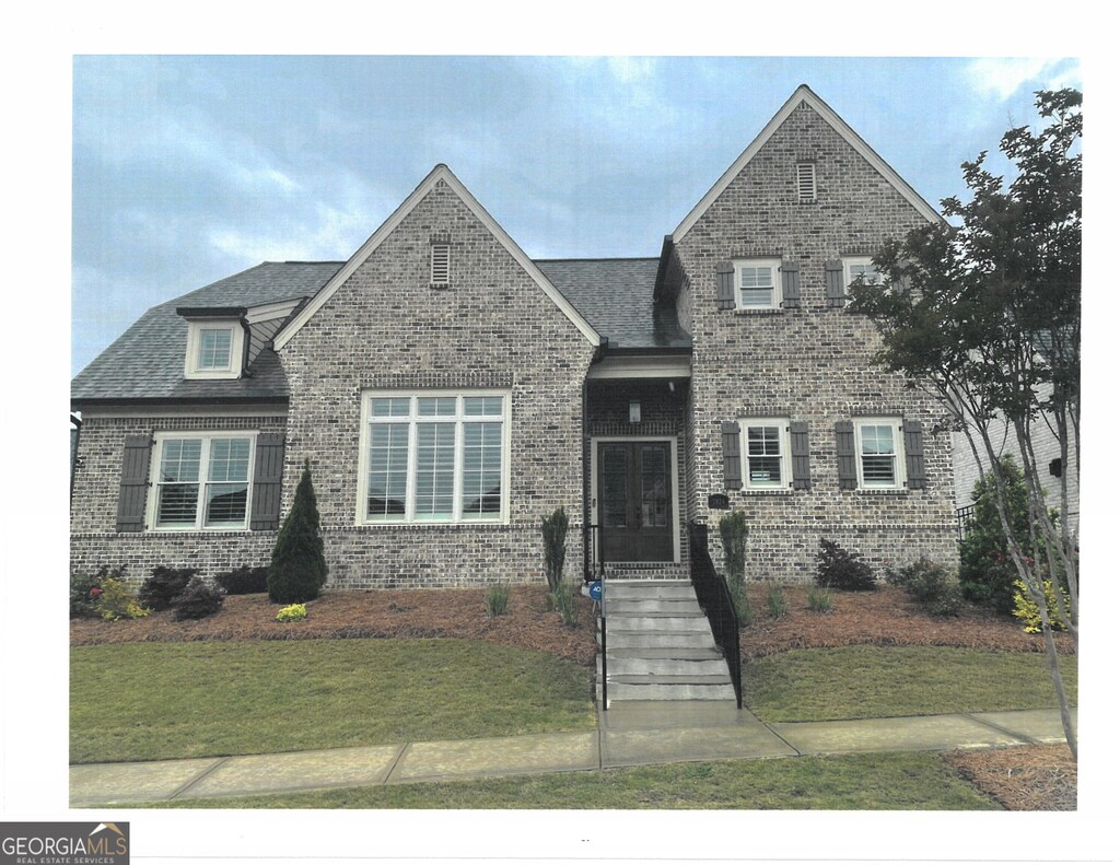 view of front of home with brick siding, a shingled roof, and a front yard
