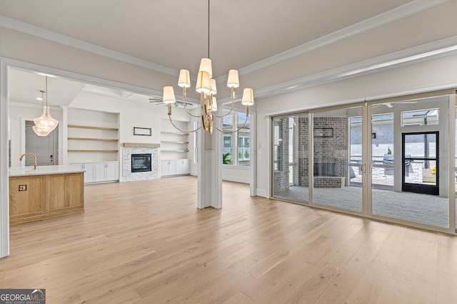 2824 Cork St, Braselton, GA 30517 - unfurnished dining area featuring light wood finished floors, ornamental molding, a chandelier, a glass covered fireplace, and built in features