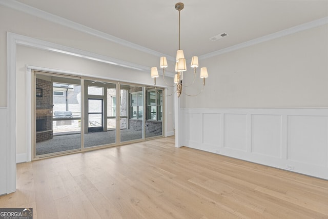 2824 Cork St, Braselton, GA 30517 - unfurnished dining area featuring crown molding, a chandelier, light wood-style floors, a decorative wall, and wainscoting